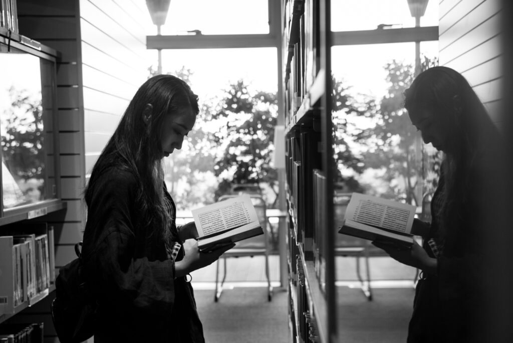 Foto de Abby Chung no Pexels: https://www.pexels.com/pt-br/foto/foto-em-escala-de-cinza-de-uma-menina-lendo-um-livro-e-refletindo-sobre-um-vidro-1061130/