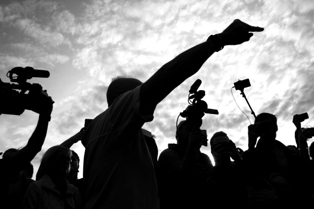 Foto de Nikita Kotrelev no Pexels: https://www.pexels.com/pt-br/foto/silhueta-de-pessoas-gravando-video-na-rua-8589617/